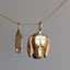 Gold pendant shaped like a dog's head on a chain against a gray background