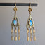 Pair of gold earrings with blue gemstones on a gray background