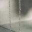 A close-up of a delicate silver chain necklace draped vertically against a soft gray background.