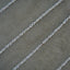 A close-up of a silver chain laid diagonally across a textured gray surface.