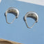 Pair of silver hoop earrings on a blue surface